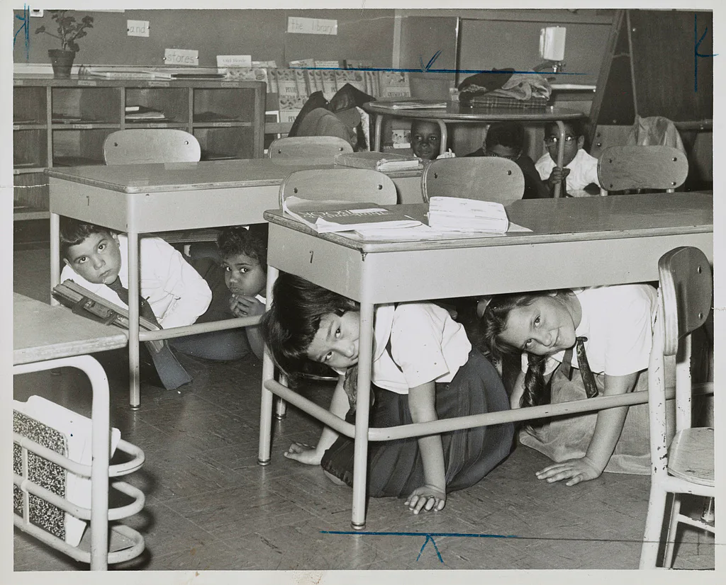 Children crouching beneath classroom desks during a take-cover drill at a Brooklyn public school