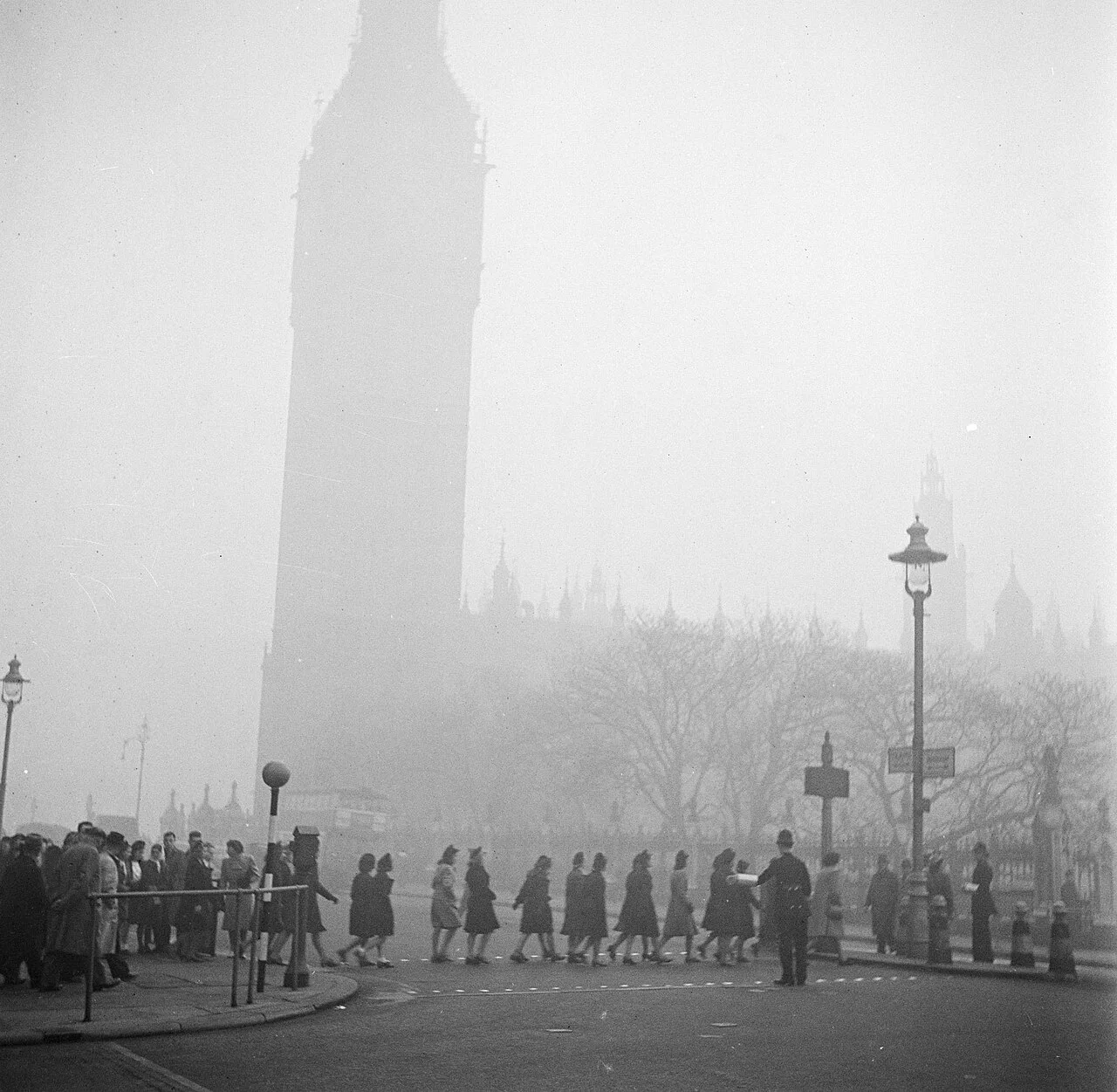 A police officer helping pedestrians cross near Big Ben during heavy London smog