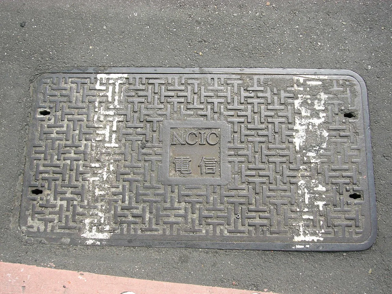 Rectangular telecommunications access cover set into a paved street