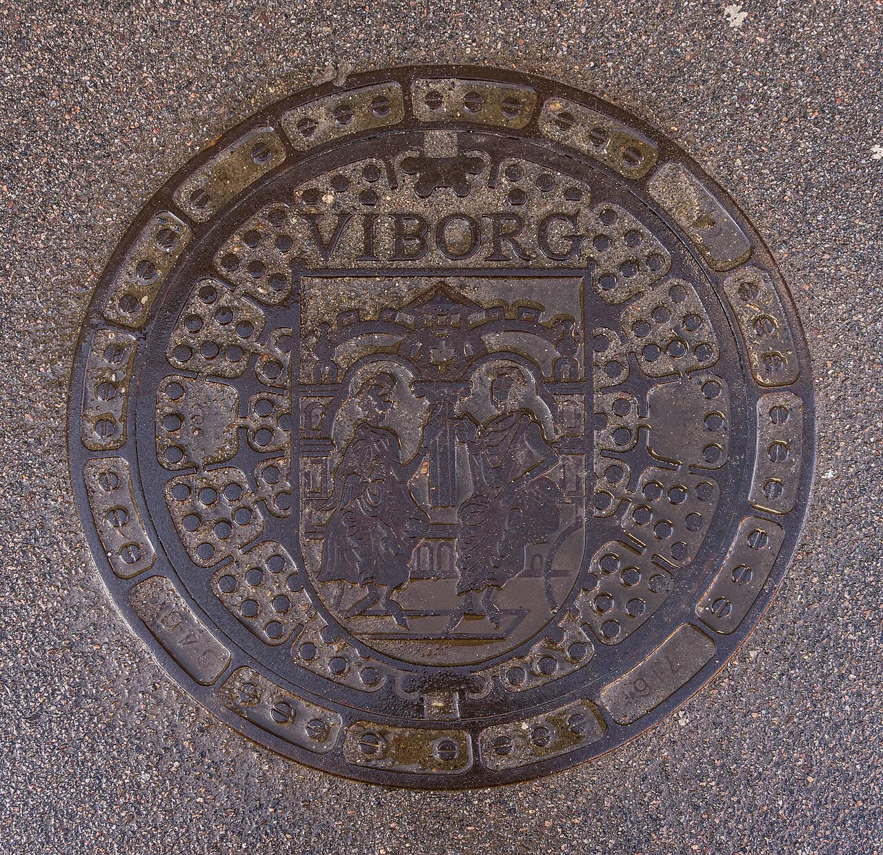 Round cast-iron manhole cover set into pavement in Viborg, Denmark