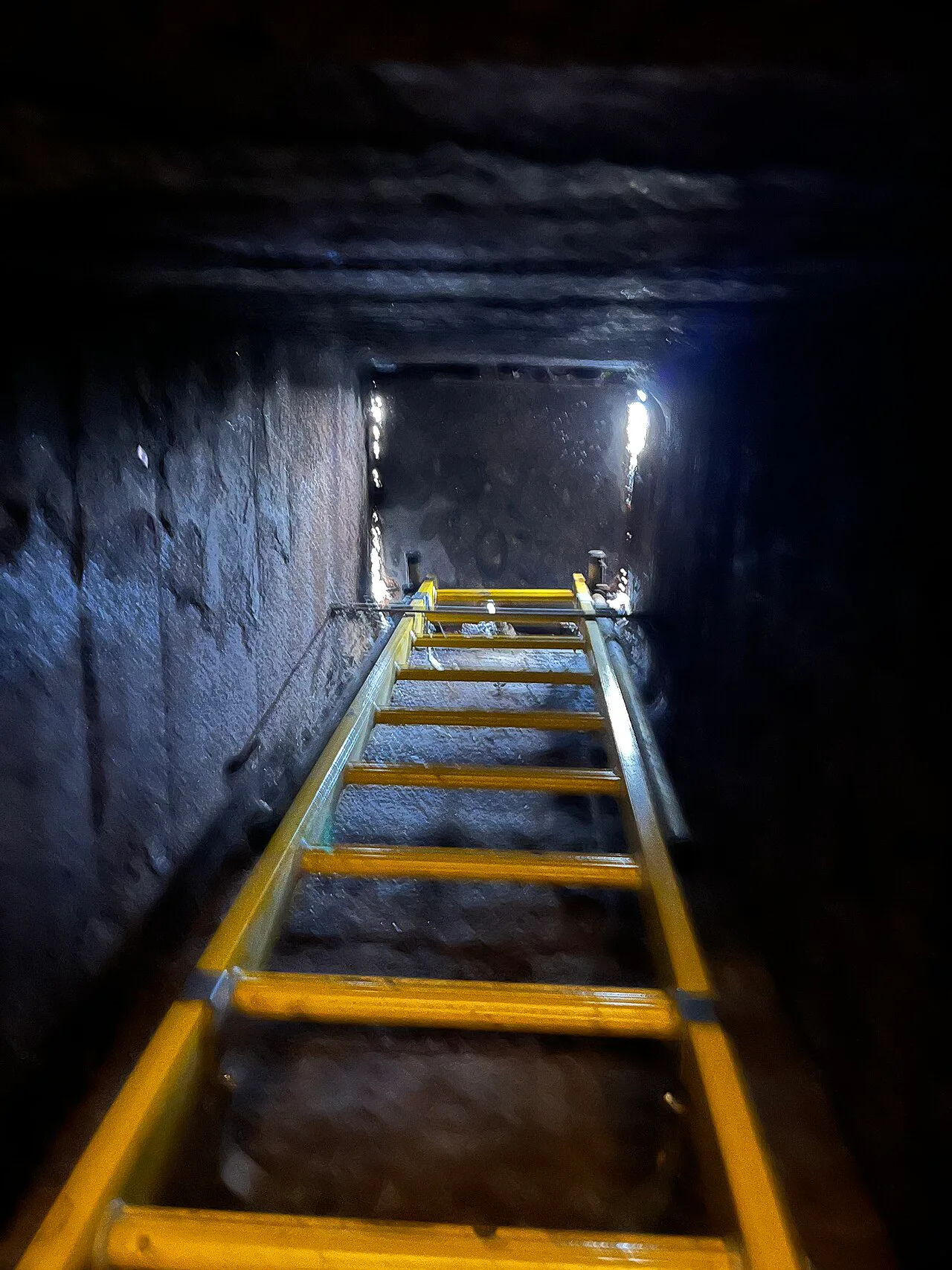 View upward through a sewer access shaft toward the underside of a manhole cover