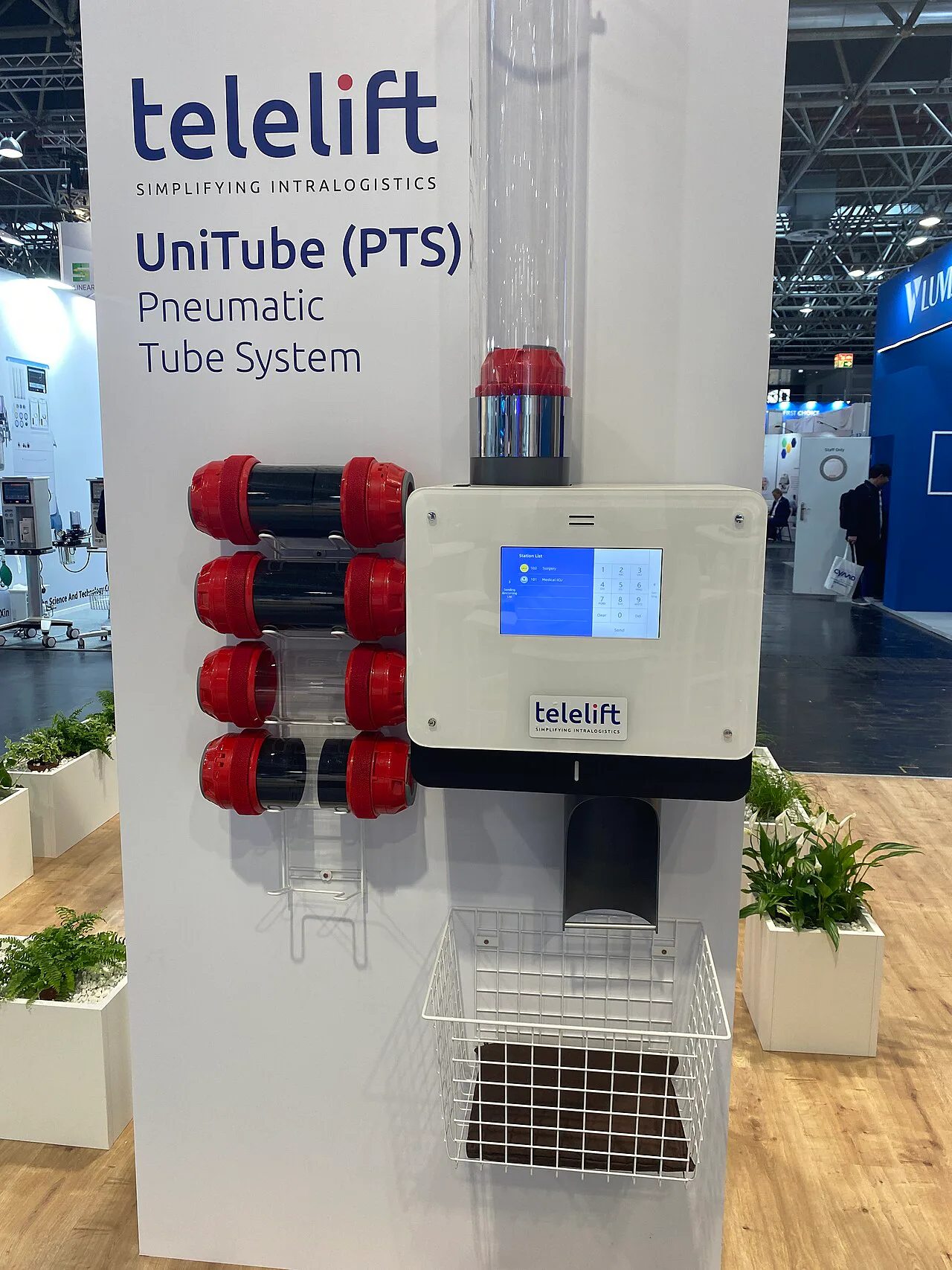 Modern pneumatic tube station with several red carriers beside a digital control panel